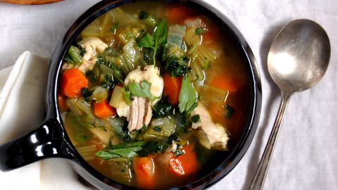 mug of the the best homemade chicken soup with bread and spoon