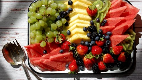 fruit platter on white tray with serving utensils