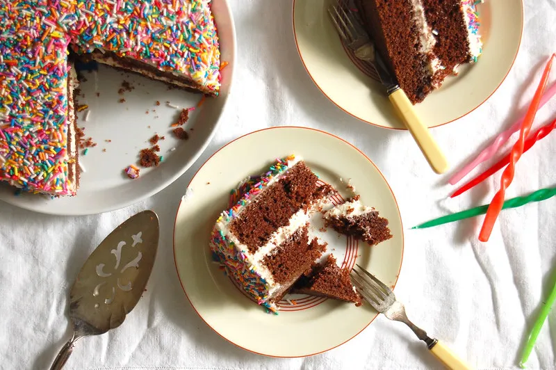 slices of birthday funfetti sprinkle chocolate cake on table with candles 