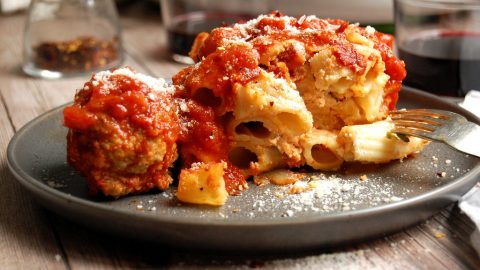 plate of a scoop of italian baked ziti with meatball on gray plate