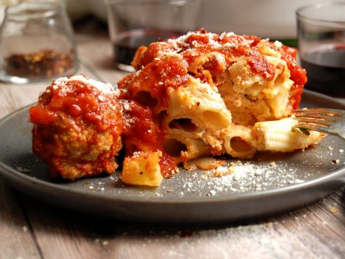 plate of a scoop of italian baked ziti with meatball on gray plate