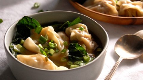 bowl of wonton soup with greens and scallions