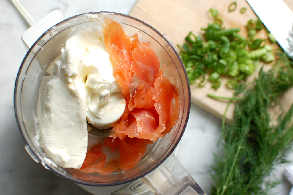Process shot of step 1 of smoked salmon cream cheese spread in a food processor with cream cheese and smoked salmon