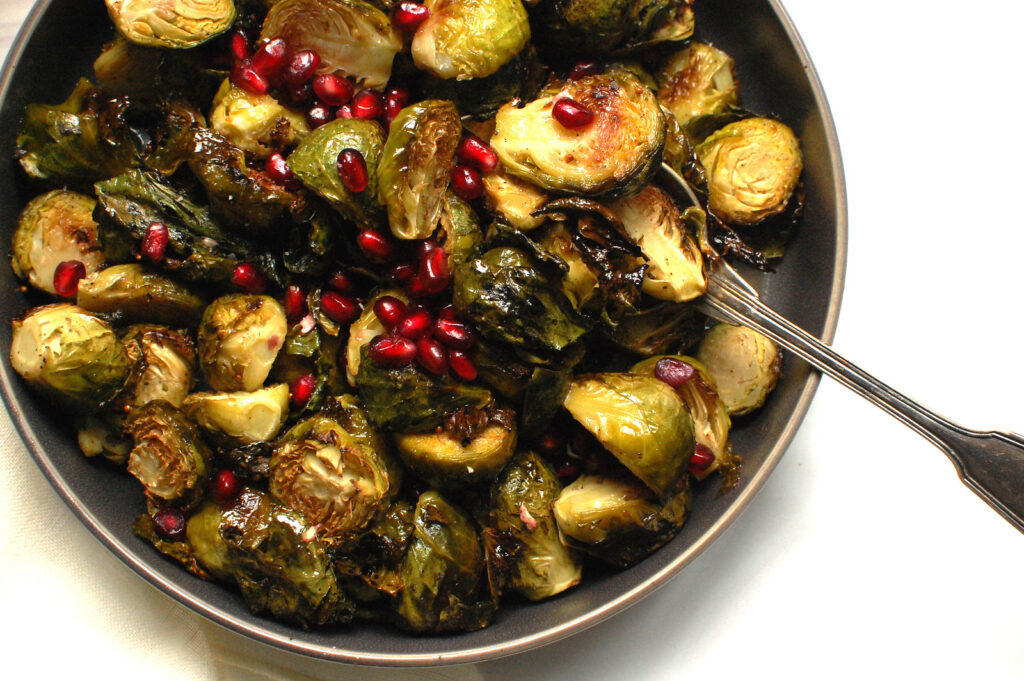 Crispy roasted Brussels sprouts with maple syrup glaze, tossed and served in a white bowl, showing their golden brown, charred edges.