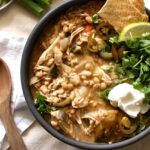 Creamy white bean chicken chili in a bowl topped with cilantro and sour cream