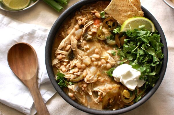 Creamy white bean chicken chili in a bowl topped with cilantro and sour cream