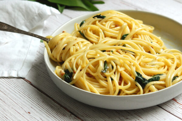 Ramp pasta carbonara with pancetta and wild ramps in a wide bowl with fork twirling strands of spaghetti coated in ramp carbonara sauce
