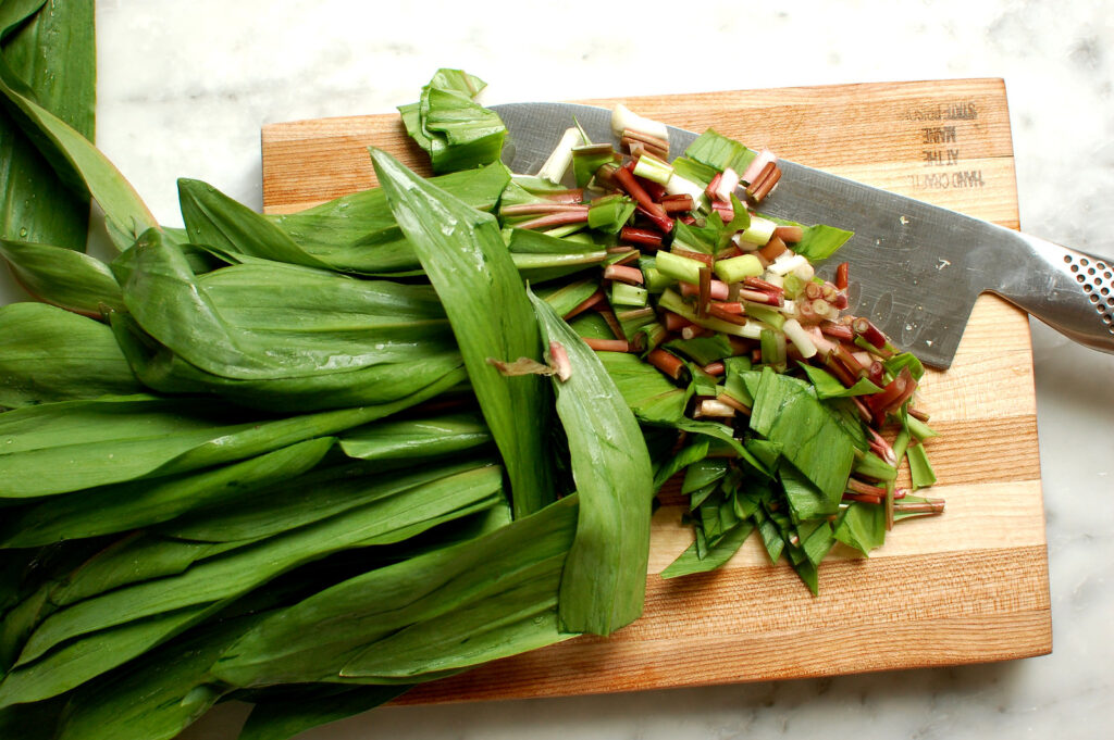 Prepped ramp bulbs and ramp leaves separated on a cutting board for pasta carbonara