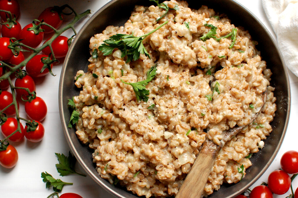 close-up image of cooked, creamy and easy farro with parmesan, broth, and parsley