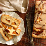baked easy peach pound cake cooling on wire rack with slices of cake on a plate to show cross-section of fruit