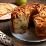 Jewish apple cake with on a cake platter, one slice cut to show layers of cinnamon apples and moist crumb