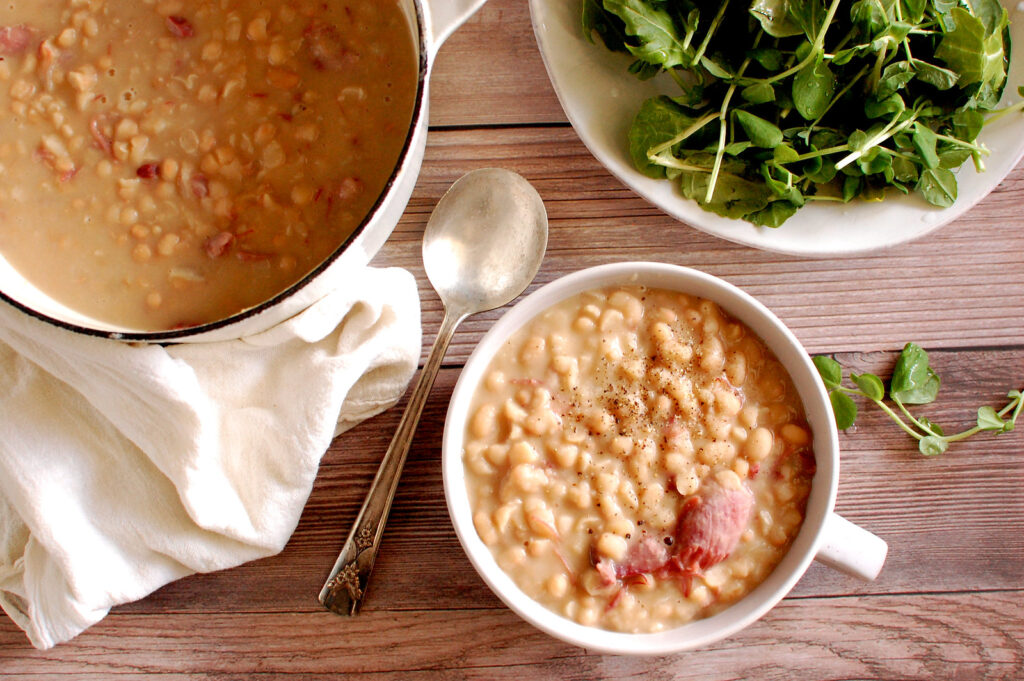 Authentic Senate Bean Soup in a bowl with smoked ham hock, navy beans, and buttery onions, traditional recipe from the U.S. Senate cafeteria