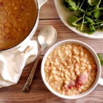 Authentic Senate Bean Soup in a bowl with smoked ham hock, navy beans, and buttery onions, traditional recipe from the U.S. Senate cafeteria