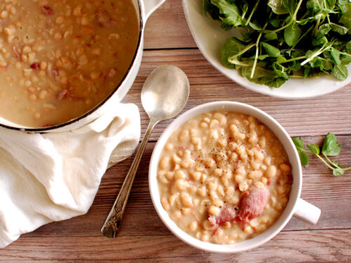 Authentic Senate Bean Soup in a bowl with smoked ham hock, navy beans, and buttery onions, traditional recipe from the U.S. Senate cafeteria