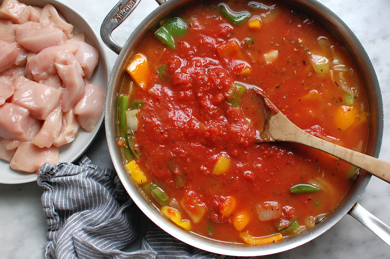 stirring tomato sauce and peppers in skillet