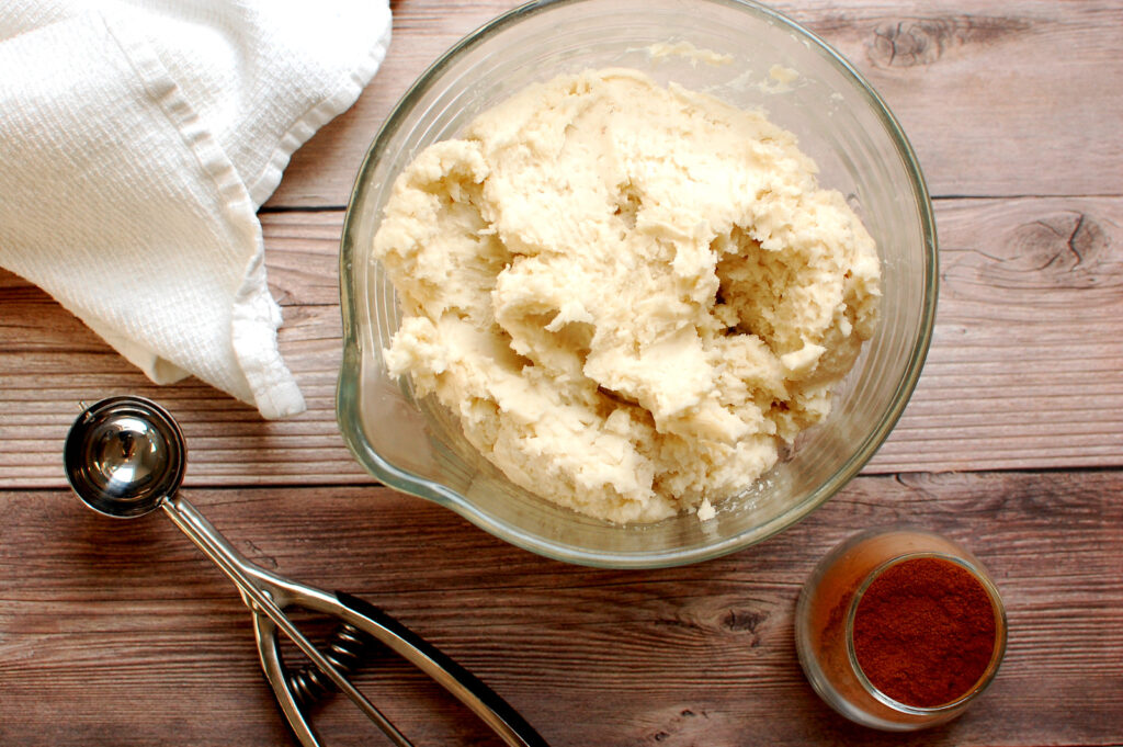 Irish potato candy coconut buttercream dough in a bowl before scooping and rolling in cinnamon.