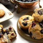 original Jordan Marsh blueberry muffins recipe, baked and served on plate with one open to show moist crumb and berries