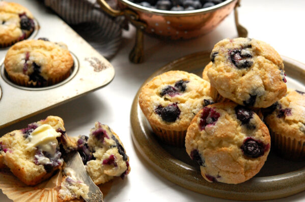 original Jordan Marsh blueberry muffins recipe, baked and served on plate with one open to show moist crumb and berries