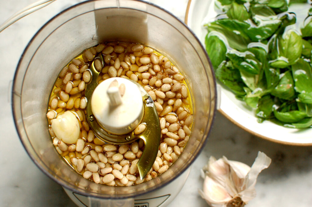 pine nuts, olive oil, and garlic in bowl of food processor before adding basil leaves to make pesto