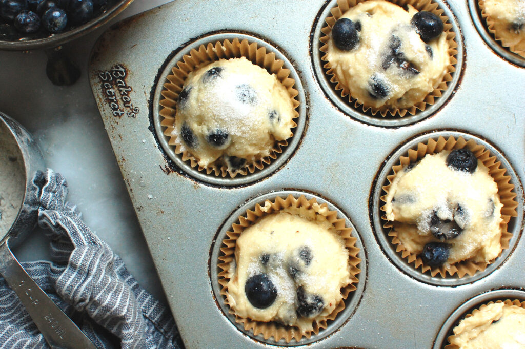 close-up of raw, scooped blueberry muffin batter in muffin cups before baking