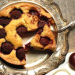 famous NYT plum torte recipe, baked and served on silver tray with slice cut out to show ripe plums