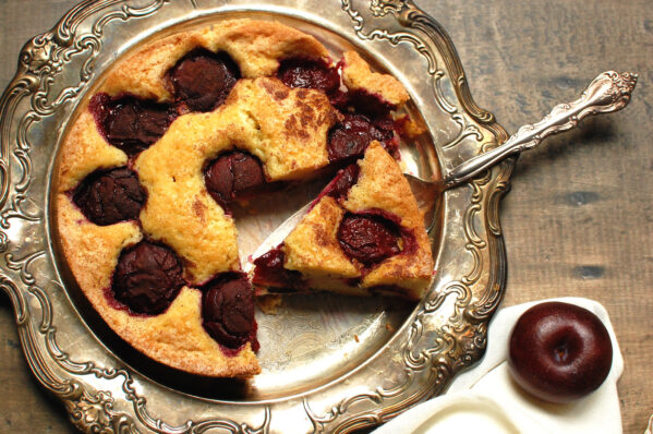 famous NYT plum torte recipe, baked and served on silver tray with slice cut out to show ripe plums