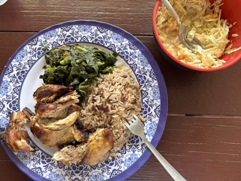 Platter of jerk chicken, callaloo, and rice and peas at Kool Vybes Jerk Center, with a side of pineapple slaw.