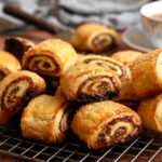 the best cinnamon rugelach cookies showing cross-section of flaky cream cheese dough layers spiraled with jammy raisin walnut filling.