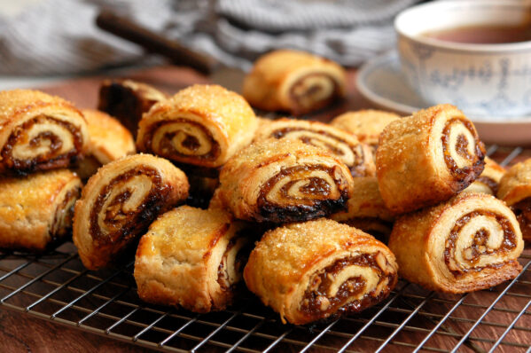 the best cinnamon rugelach cookies showing cross-section of flaky cream cheese dough layers spiraled with jammy raisin walnut filling.