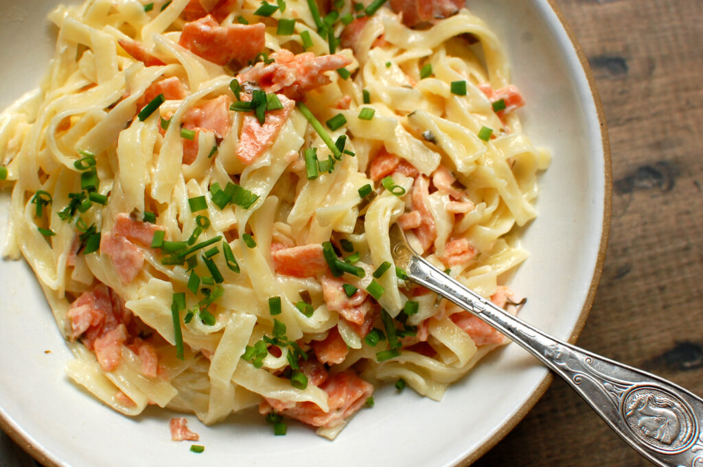 close-up image of fork twirling quick 20-minute smoked salmon pasta with a silky lemon cream sauce to show texture and color. 