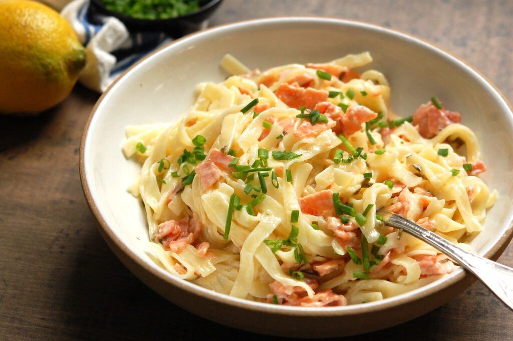 Easy smoked salmon pasta with creamy sauce, lemon, fresh chives, and lemon zest in bowl, ready to serve