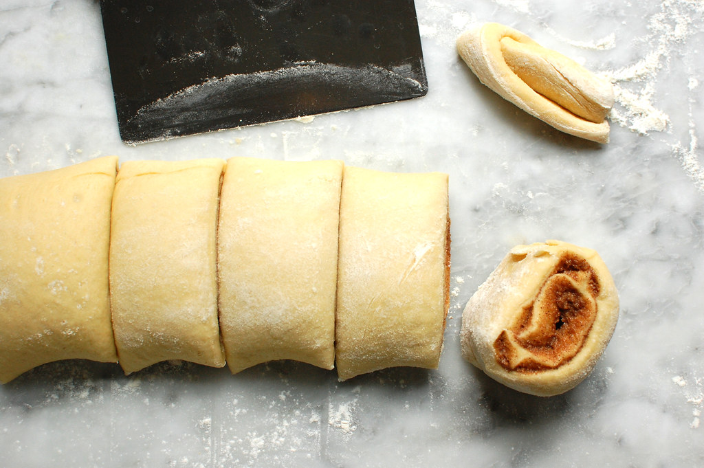 log of rolled dough being cut into individual rolls