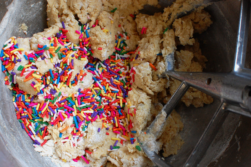 rainbow sprinkles getting mixed into cookie dough in bowl