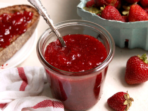 Homemade strawberry preserves in a glass jar with elegant silver spoon, made with fresh strawberries and no pectin