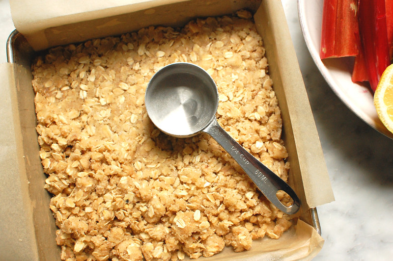 buttery oat crumble crust in baking pan before adding strawberry rhubarb filling
