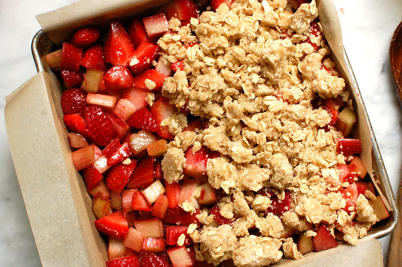 oat streusel baking laid on top of fruit filling in baking pan