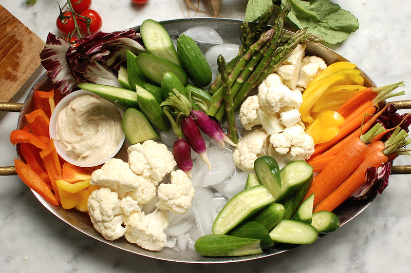 arranging raw crudite vegetables on tray