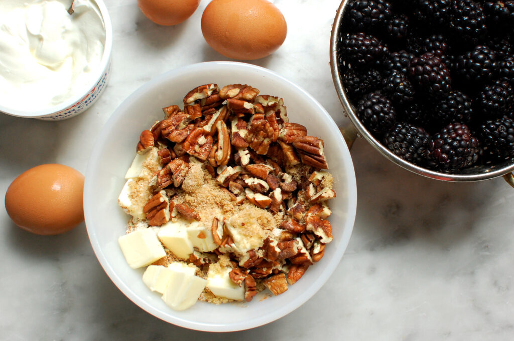 coffee cake streusel topping being made next to bowl of blackberries
