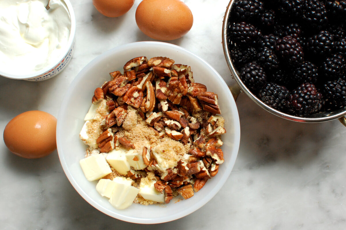 coffee cake streusel topping being made next to bowl of blackberries