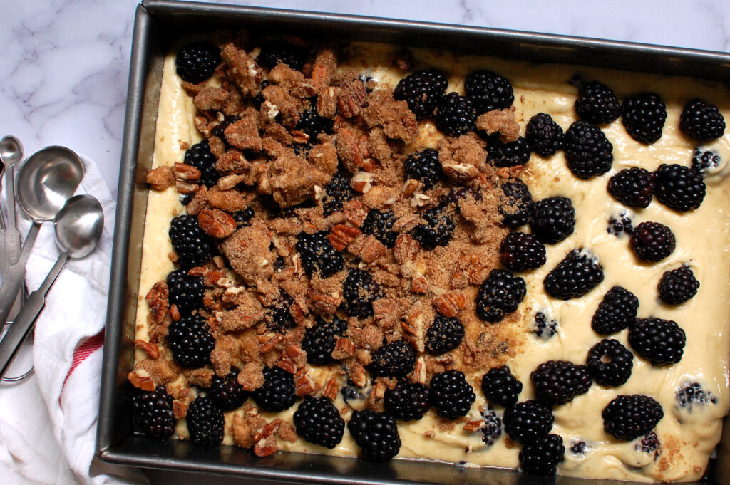 recipe step adding pecan streusel topping to blackberry coffee cake batter before baking