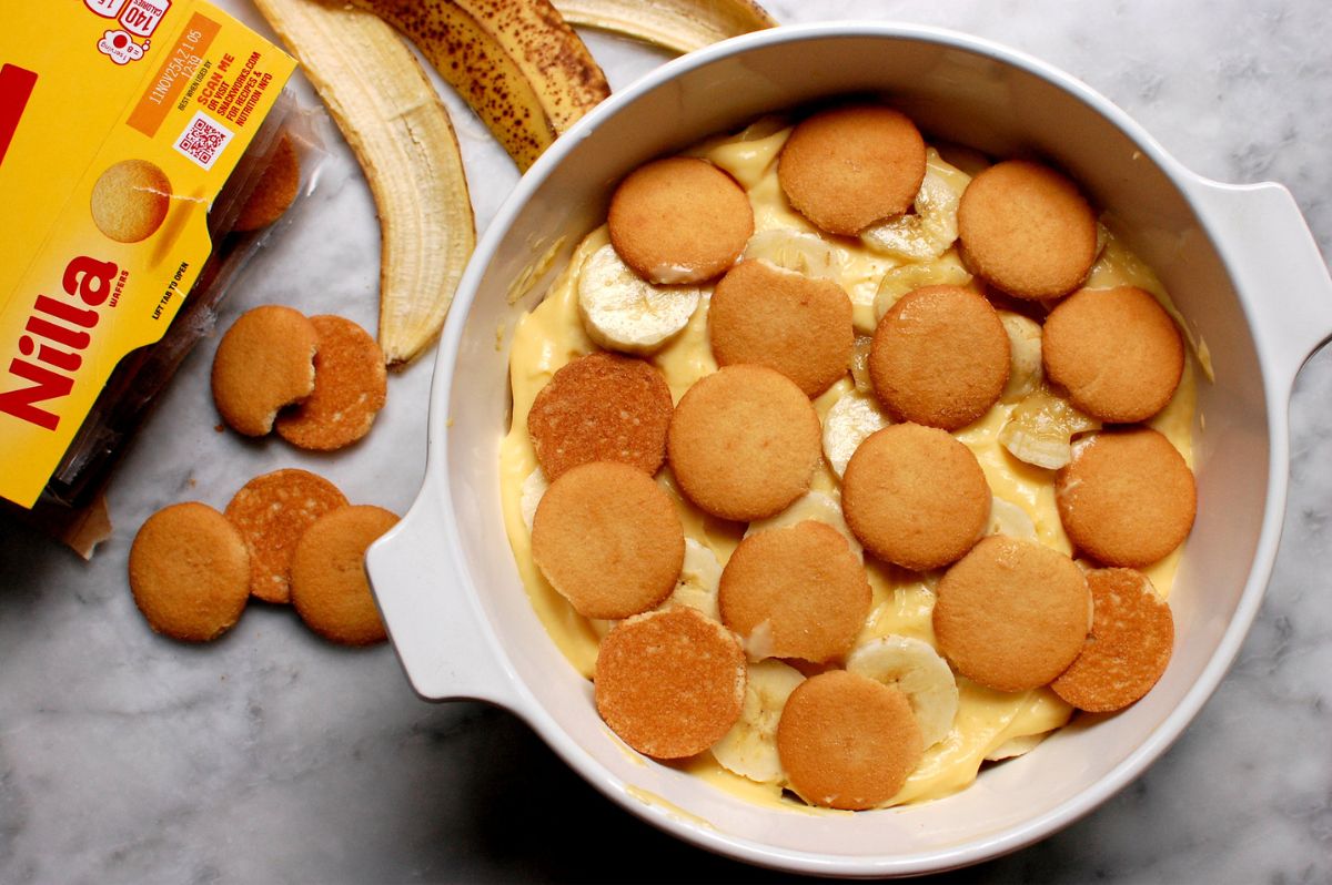 Layering fresh bananas and vanilla wafers on top of vanilla custard in a baking dish for traditional Southern banana pudding.
