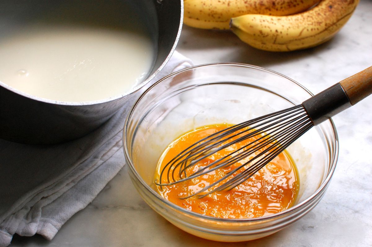 Whisking eggs and sugar in bowl, about to add hot milk for Southern banana pudding from scratch.