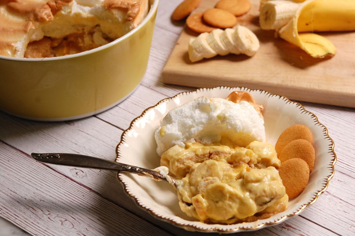 Classic banana pudding with meringue, layered with custard, bananas, and vanilla wafers, served in a bowl.