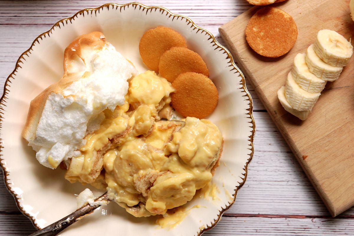 Close-up serving of classic banana pudding with meringue, layered with custard, bananas, and vanilla wafers, served in a bowl.