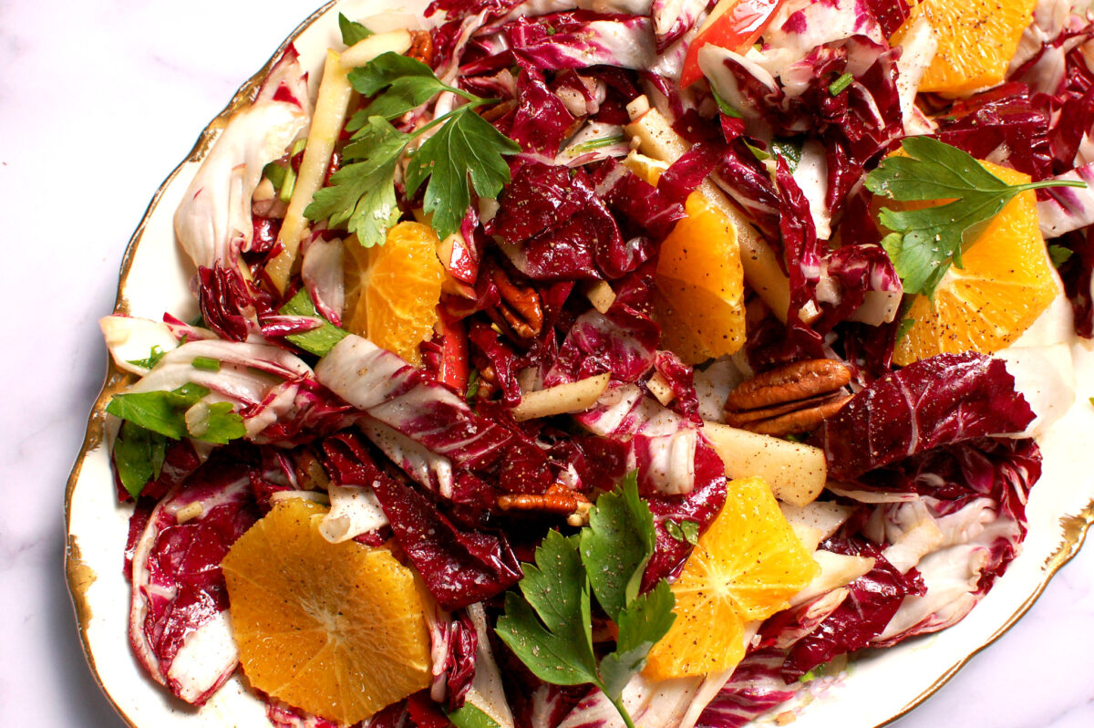 Close-up of radicchio salad showing citrus, apple matchsticks, herbs, and toasted pecans.