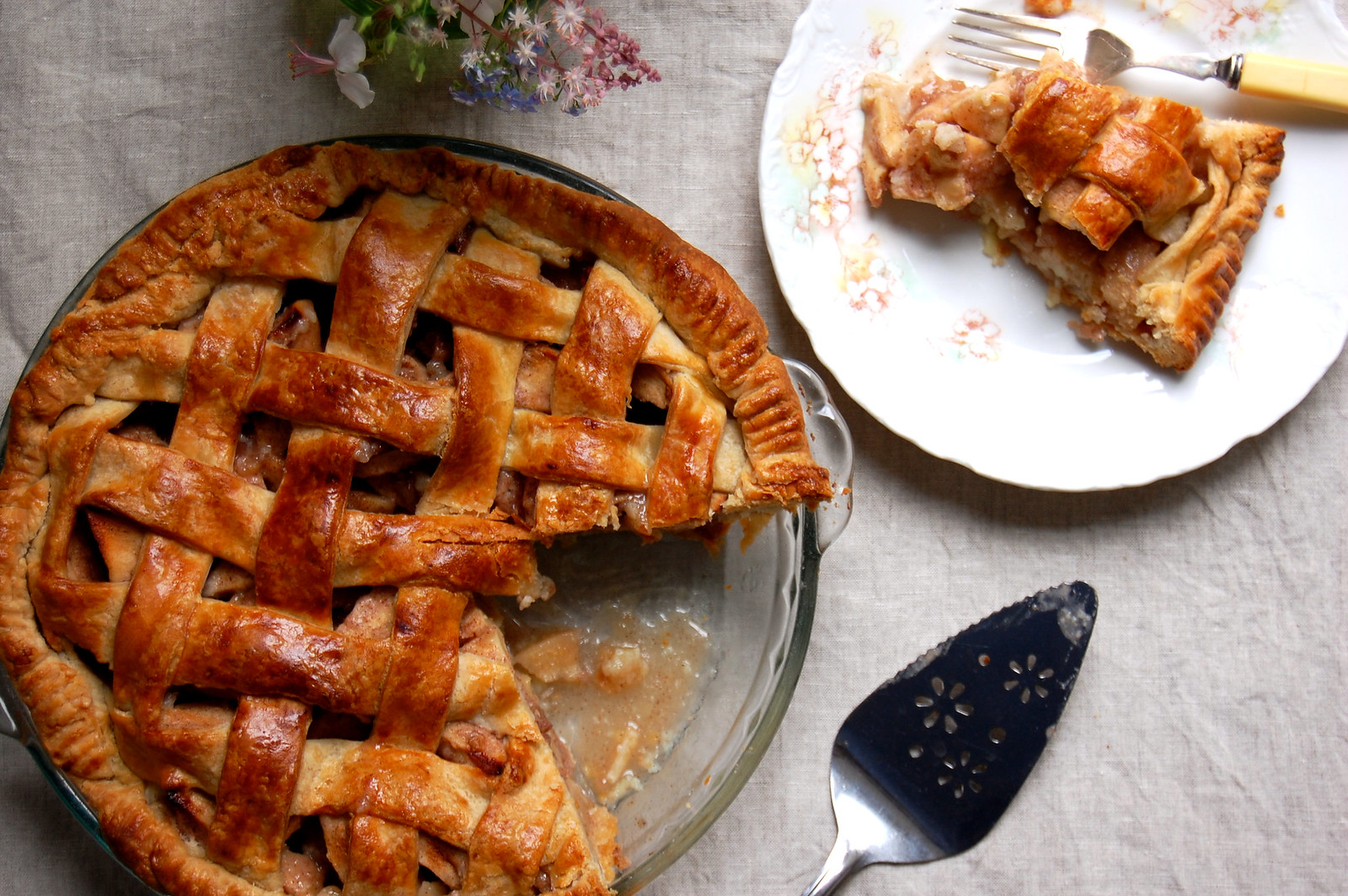 The Best Thanksgiving dessert apple pie in pie plate with slice on dish with fork