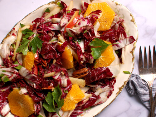 radicchio salad with citrus, apple slices, herbs, cheese, and toasted pecans on serving platter.