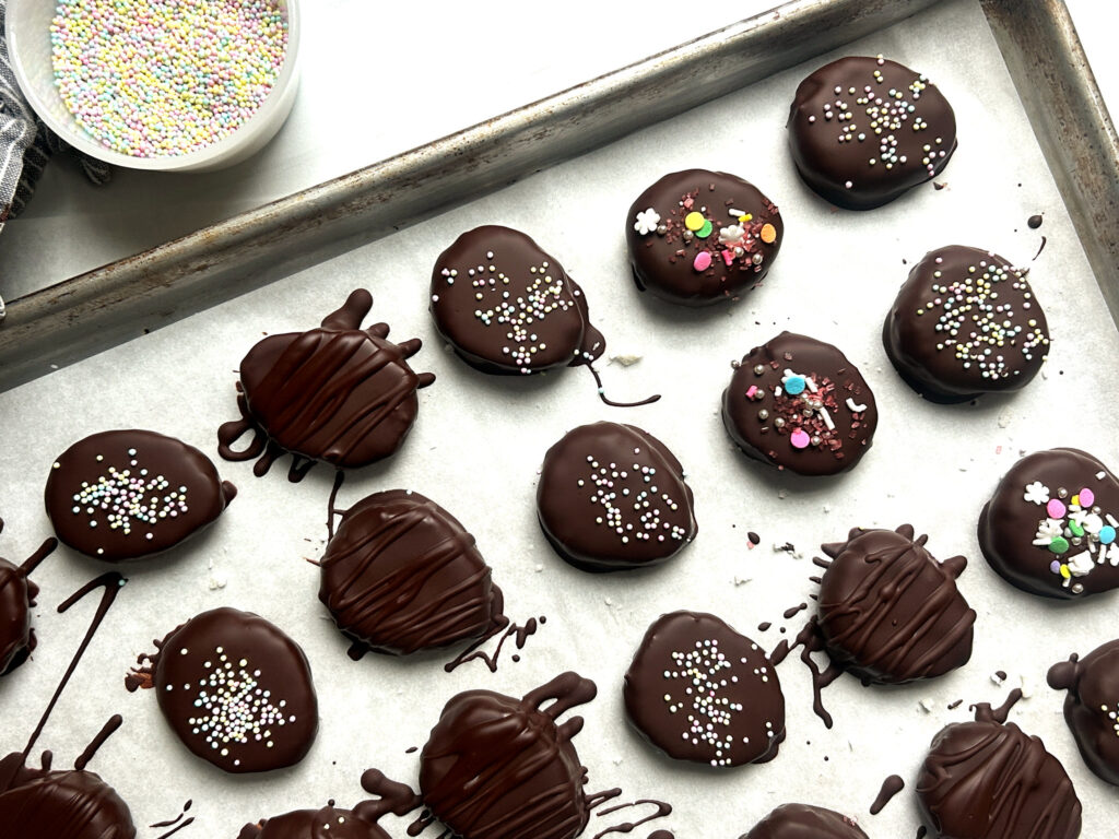 homemade chocolate-dipped coconut cream Easter eggs with sprinkle decorations, drying on parchment-lined sheet pan to show how to dip and decorate