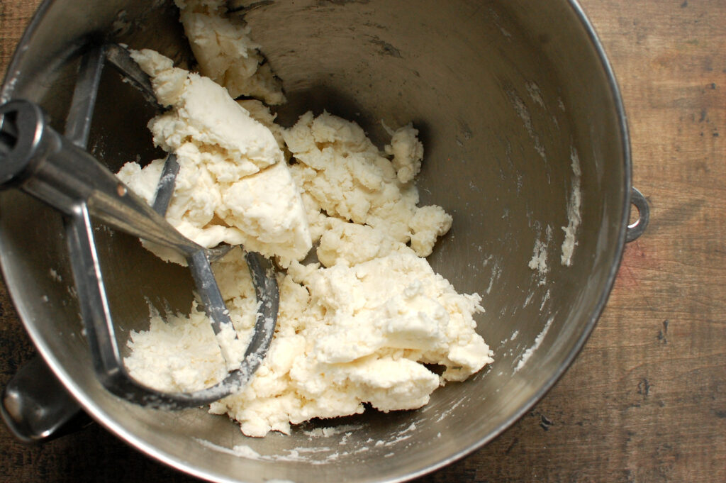 Coconut cream filling mixture fully mixed in bowl of electric mixer with paddle