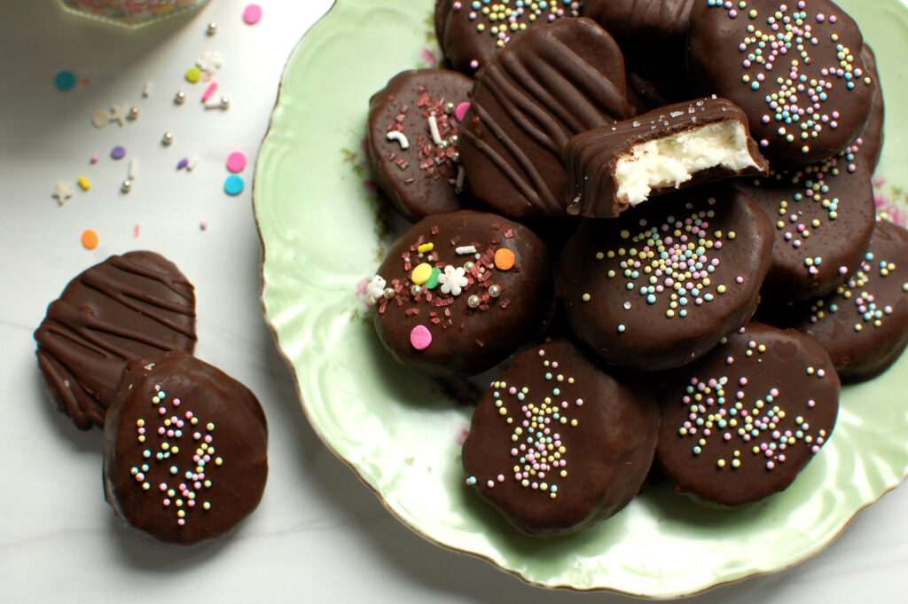 Homemade chocolate coconut cream eggs with a bite taken out, showing the moist coconut cream Easter egg center and dark chocolate coating.